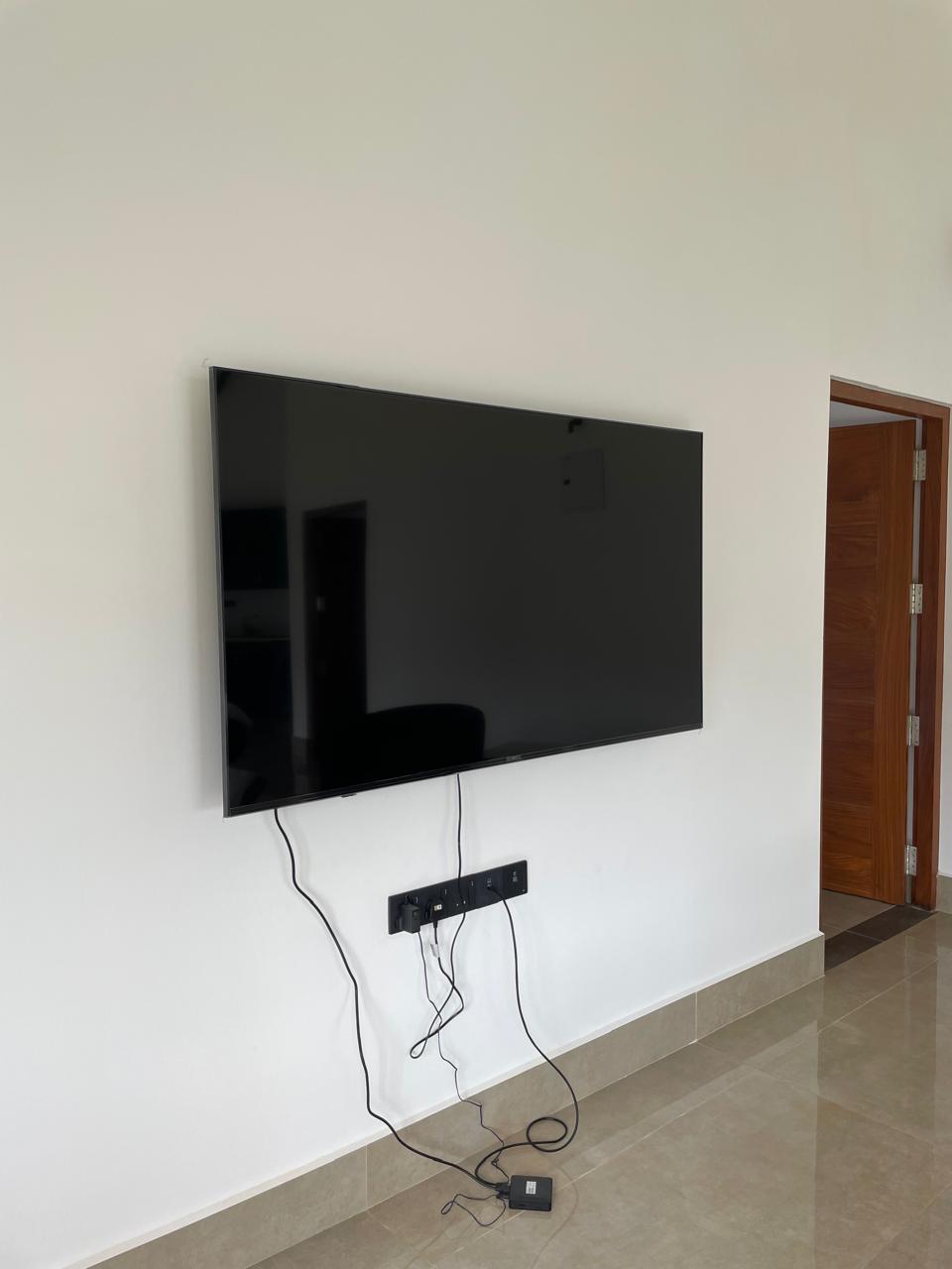 Lounge wall with mounted flat-screen smart TV beside the bedroom door