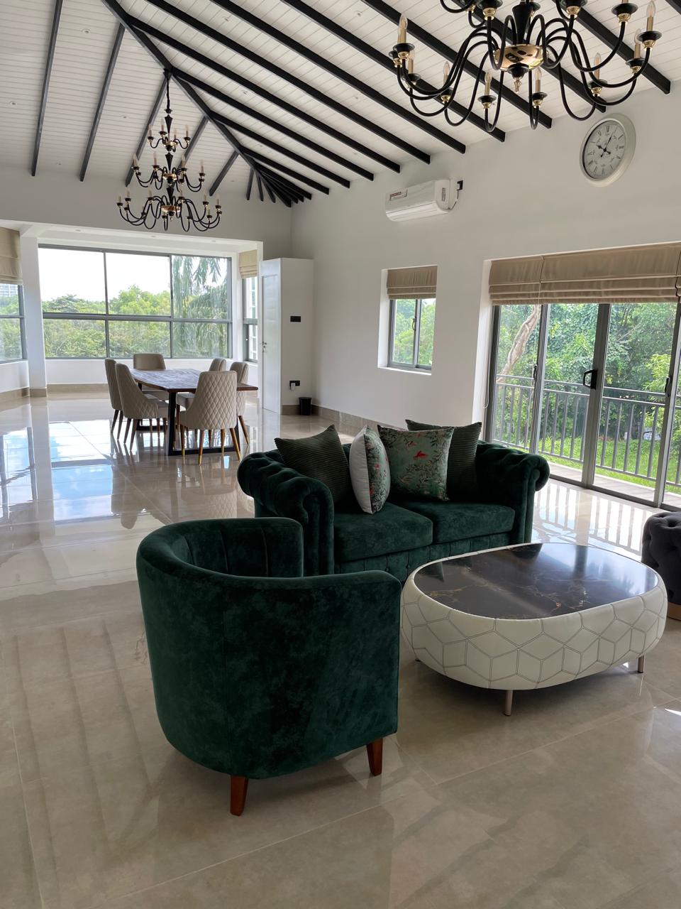 Penthouse living room with emerald velvet sofas, marble coffee table and beamed cathedral ceiling