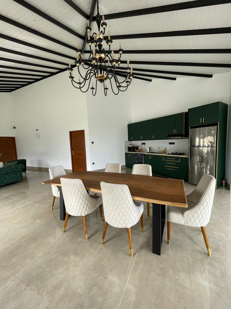 Live-edge hardwood dining table with cream quilted chairs beneath a chandelier