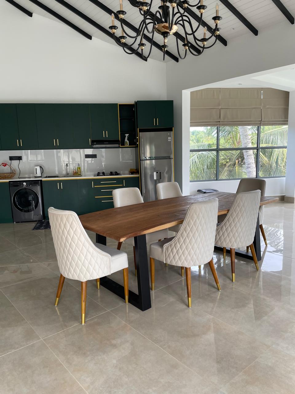 Live-edge hardwood dining table with cream quilted chairs beneath a chandelier